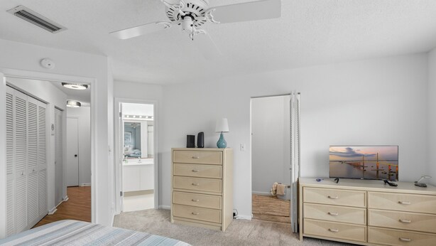 Een slaapkamer met een bed, een kaptafel, een vensterbank met spiegel en een televisie op een dressoir.