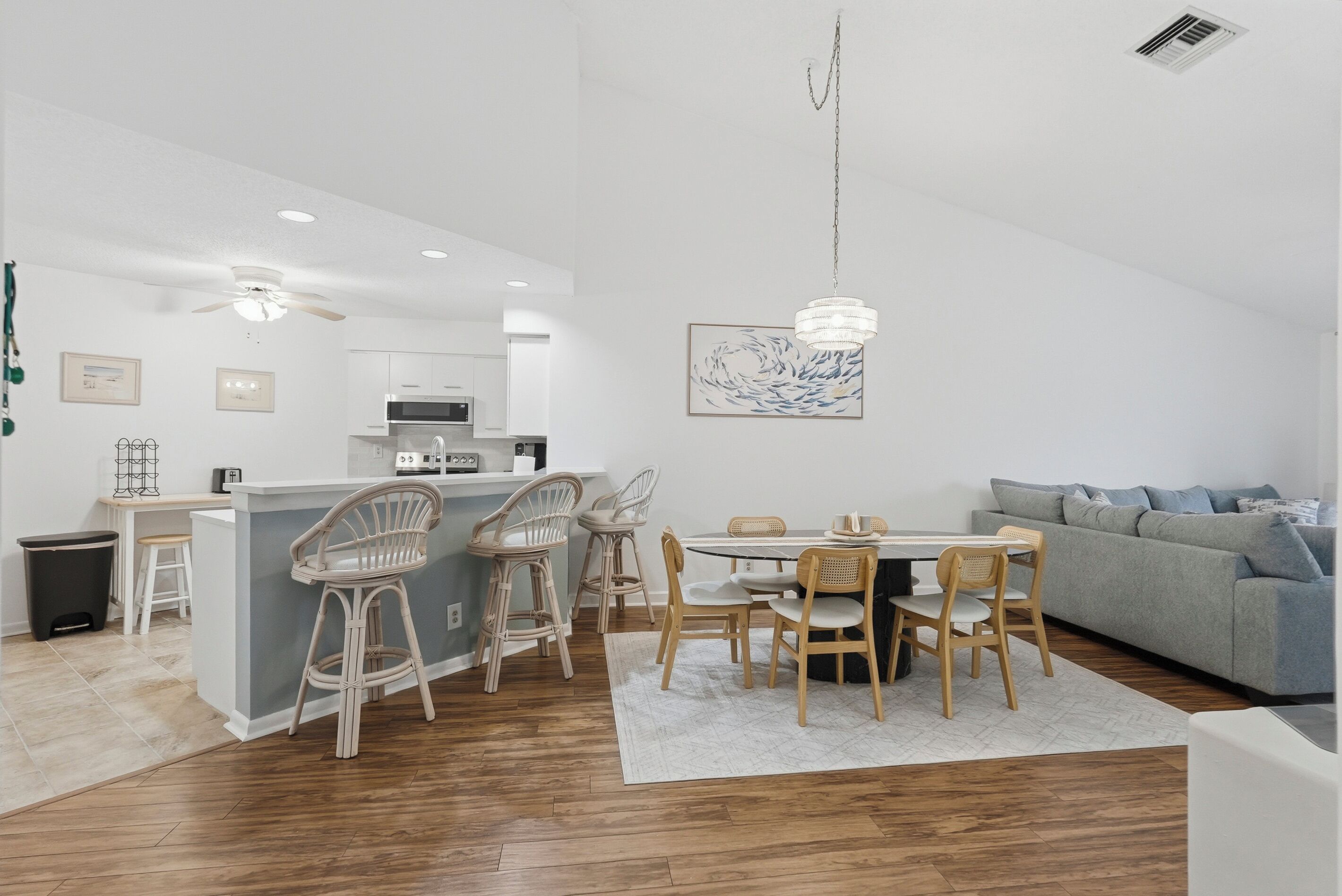 Une cuisine moderne avec des meubles blancs, un îlot central doté de tabourets, et un coin repas avec une table ronde et des chaises.