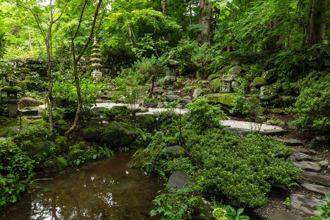 A serene garden with a stone pathway, a small stream, and traditional stone lanterns.