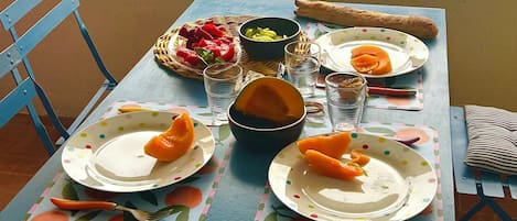 A dining table with plates, bowls, and cutlery on a balcony overlooking a beach.