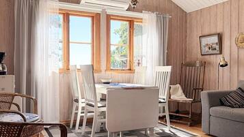 A room with a dining table, chairs, a sofa, a lamp, and a picture on the wall.