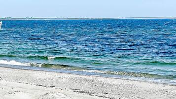 A beach with clear blue water and a sandy shore.