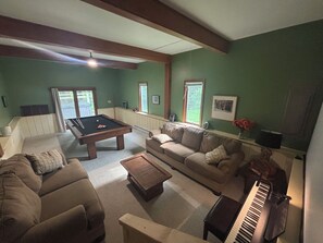 A living room with a pool table, a sofa, a coffee table, and a piano. - Lakeview~Hot Tub~Fire Pit~Pool Table~Acre+~Dog Friendly (Blakeslee)