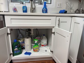 A kitchen with a white countertop, a window above the sink, and various cleaning supplies. - Lakeview~Hot Tub~Fire Pit~Pool Table~Acre+~Dog Friendly (Blakeslee)