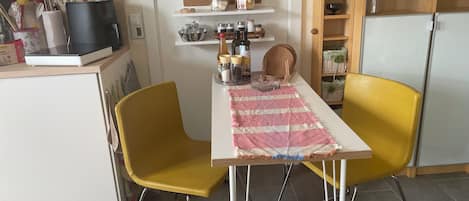 A kitchen with a dining table, chairs, and various kitchen items.
