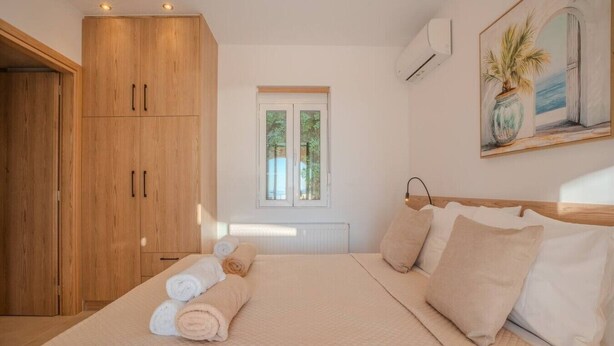 Um quarto com uma cama, uma janela, um quadro e móveis de madeira.