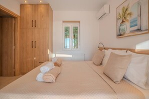 A bedroom with a bed, a window, a painting, and wooden furniture. - Luxury Villa with unlimited sea view (Chania)