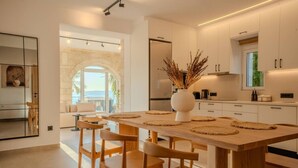 Uma cozinha moderna com ilha central, armários brancos e vista para o exterior.