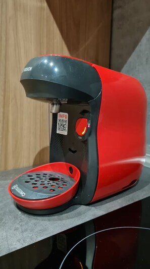 Una máquina de café roja y negra con un código QR y un botón rojo en el lateral.