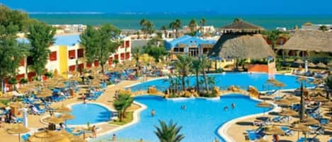 A resort with multiple swimming pools, sun loungers, and thatched-roof structures.