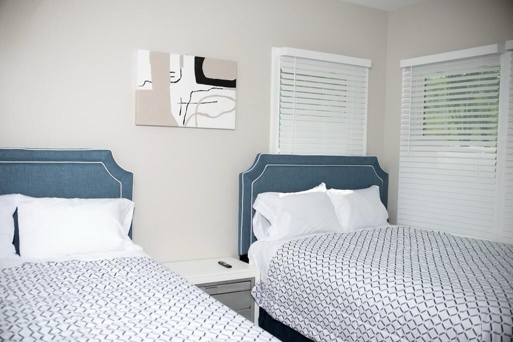 A hotel room with two beds, a nightstand, and a wall-mounted abstract painting.