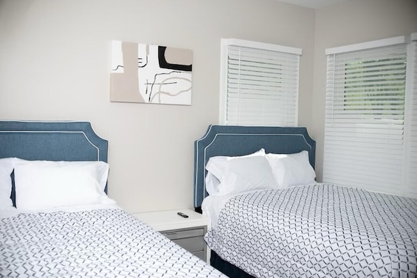 A hotel room with two beds, a nightstand, and a wall-mounted abstract painting.