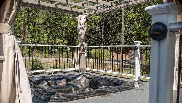 Et overdækket udeområde med jacuzzi, pergola og gelænder i hvid.