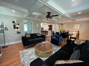 A modern living room with a black sofa, a round coffee table, and a ceiling fan.