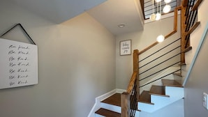 A staircase with wooden steps and a handrail, a wall-mounted sign with the phrase 'Be Kind,' and a framed sign that says 'today I choose joy.'