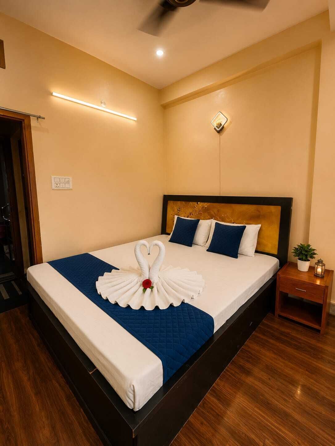 Habitació d'hotel amb un llit, una tauleta de nit, una làmpada penjada a la paret i un ventilador de sostre.