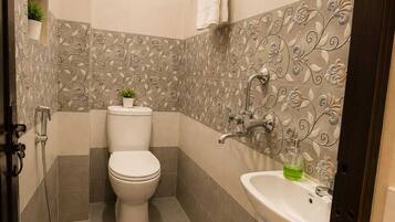 Baño con inodoro, lavamanos, ducha y azulejos decorativos.