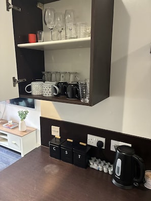 Eine Küche mit eingebautem Regal, das Glaswaren, Tassen, eine Kaffeemaschine und Gewürzbehälter beherbergt.