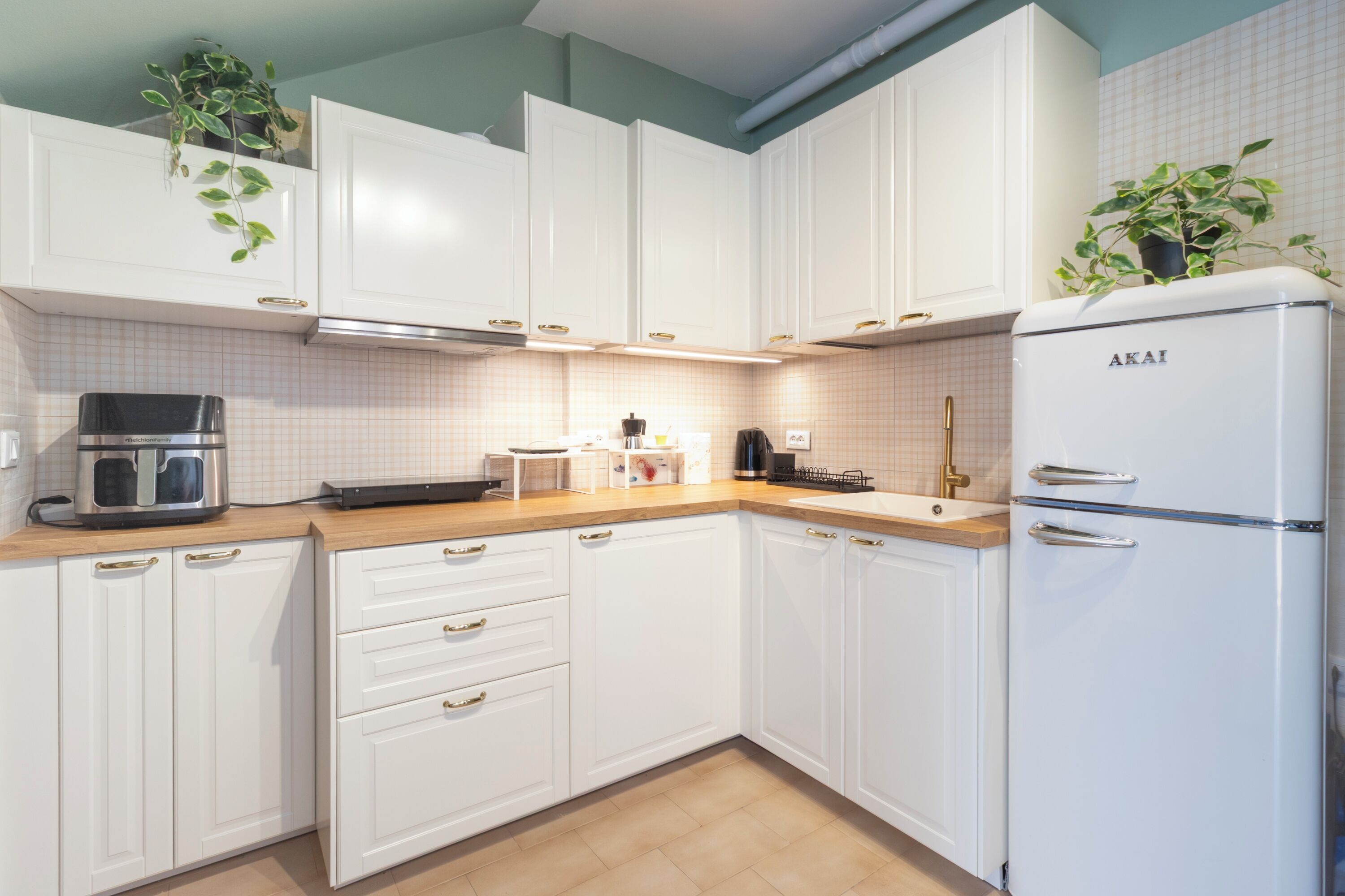 A modern kitchen with white cabinets, a built-in oven, and a refrigerator.
