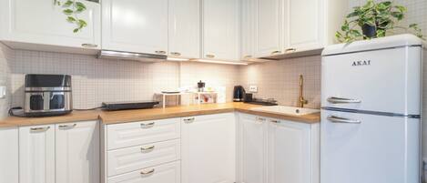 A modern kitchen with white cabinets, a built-in oven, and a refrigerator.