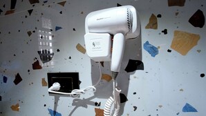 Ein an der Wand befestigter Haartrockner in einem Hotelzimmer, mit Kabel.