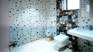 Ein Badezimmer mit Terrazzo-Boden, Toilette, Waschbecken und Spiegel.