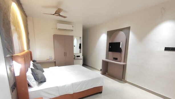 Ein modernes Schlafzimmer mit Bett, Schminktisch, Fernseher und Deckenventilator.