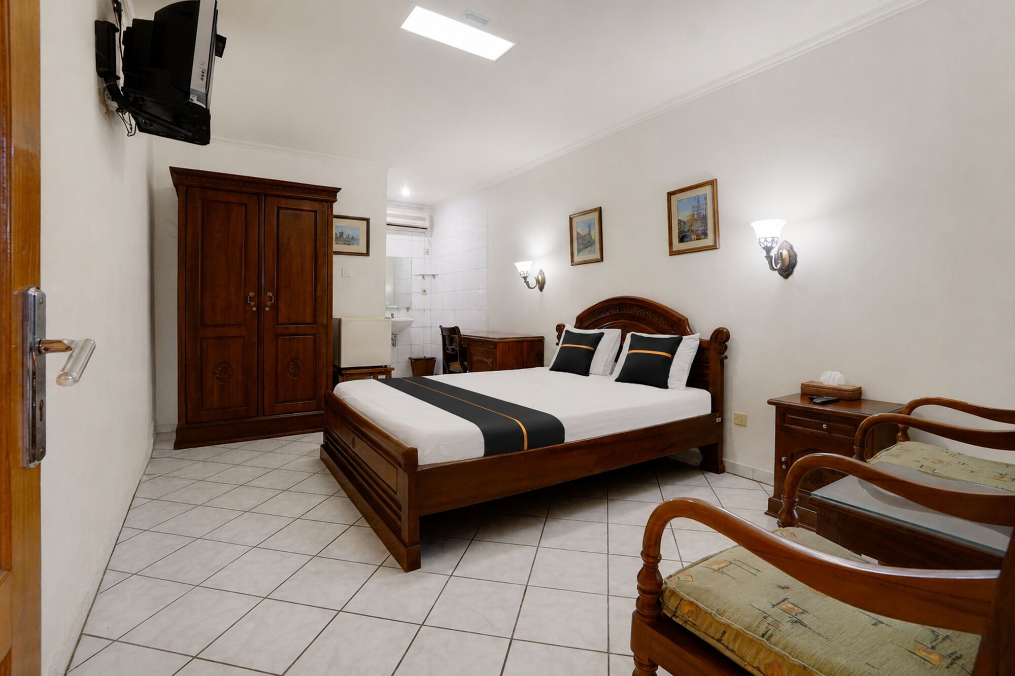 A hotel room with a large bed, a wardrobe, a desk, and a chair.