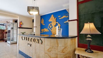 A reception desk with a sign reading 'Winston Hotel,' a reception area with a blue wall, a fire extinguisher, a lamp, and a glass display case.
