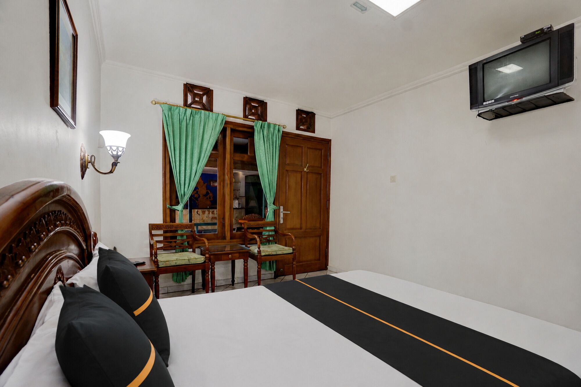 A hotel room with a bed, a TV, a wooden wardrobe, a desk, and a chair.