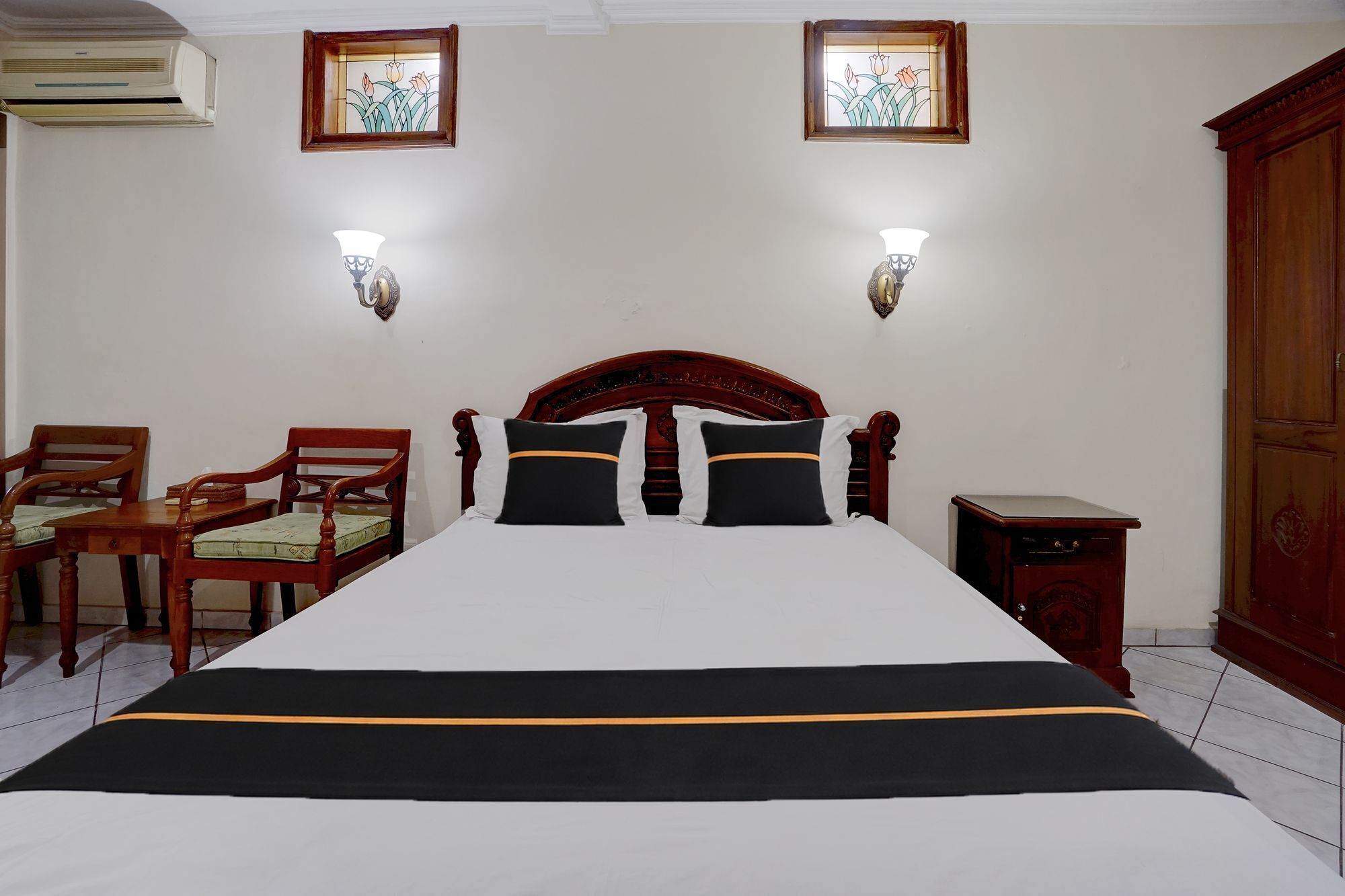 Ein Hotelzimmer mit einem großen Bett, zwei Wandlampen, einem Holzschrank und einem kleinen Tisch.