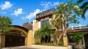 A hotel entrance with a sign reading 'Hotel WISTON,' a gated driveway, and surrounding greenery. - Hotel O near City of Tomorrow Mall (Surabaya)