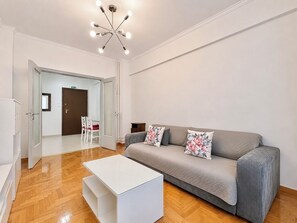 A modern living room with a grey sofa, white coffee table, and a ceiling light fixture. - Athens Metro Escape - Central & Connected by ΜΡS (Athina)