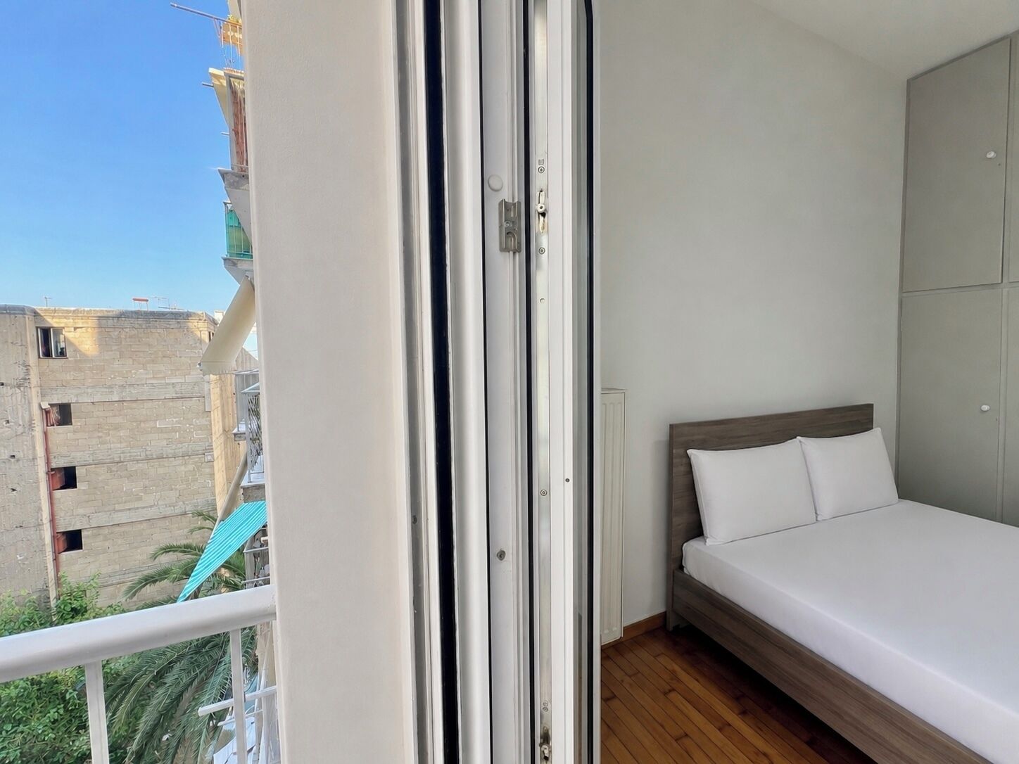 Un dormitorio con cama, armario y vistas a edificios.