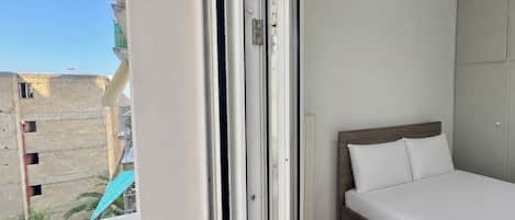 Un dormitorio con cama, armario y vistas a edificios.