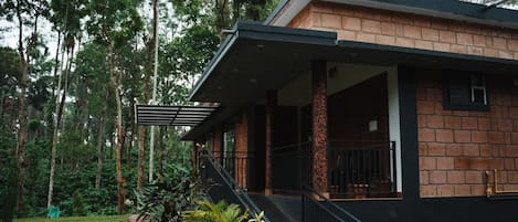 A house with a covered porch, a brick exterior, and a garden with various plants.