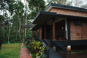 Una casa con porche cubierto, fachada de ladrillo y jardín con diversas plantas.