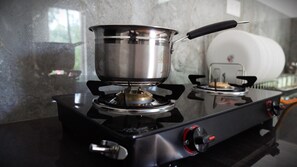 Una estufa a gas con una olla encima, un quemador de gas y una perilla.