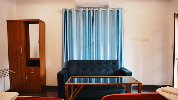 A room with a wardrobe, a sofa, a coffee table, and two beds.