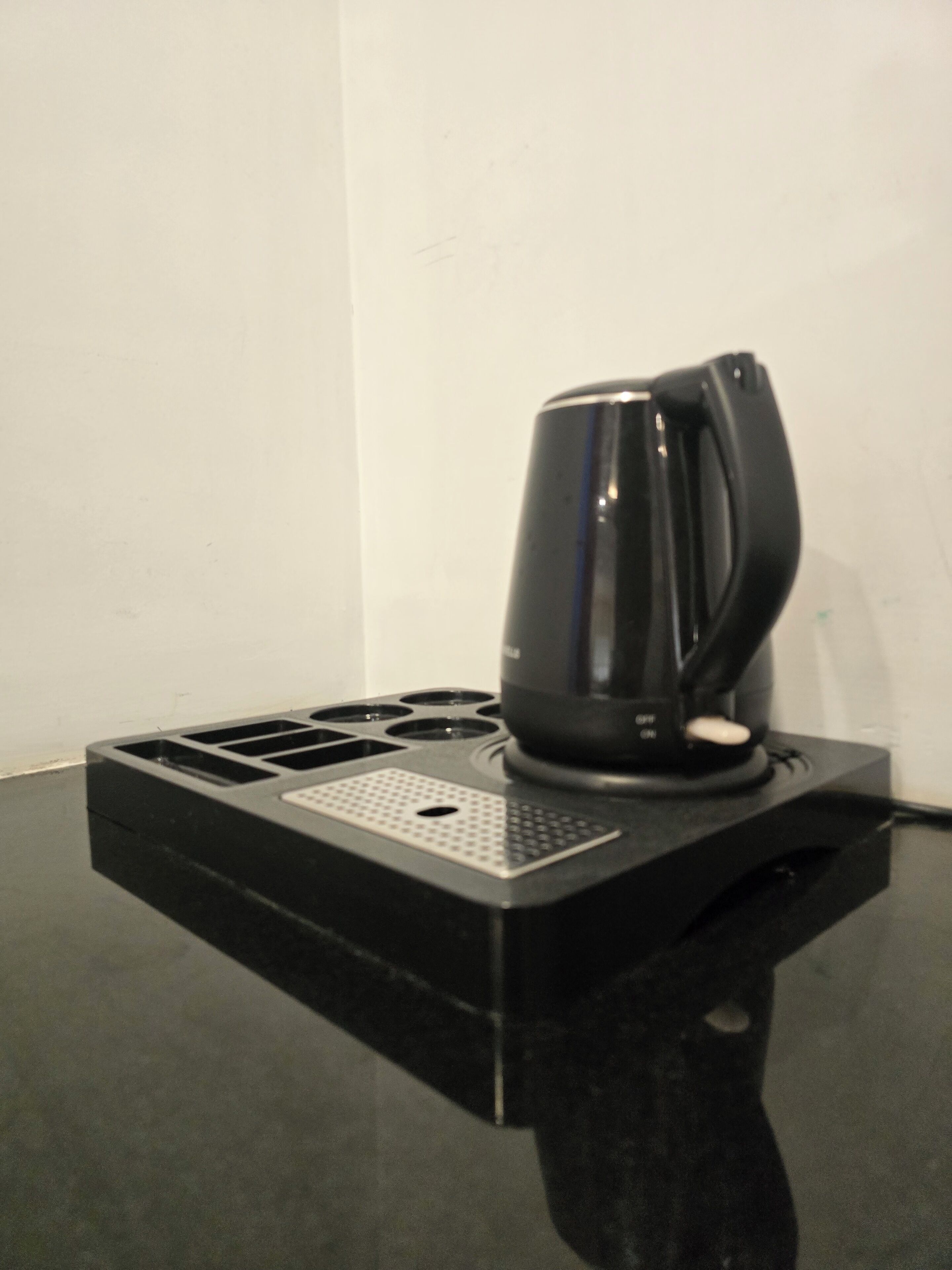 A black coffee maker on a black countertop with a control panel.