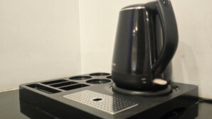 A black coffee maker on a black countertop with a control panel.