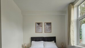 A bedroom with a large bed, two bedside tables, and a window with curtains. - Luxury Flat 10 Mins from Station + Bike ! (Cambridge)