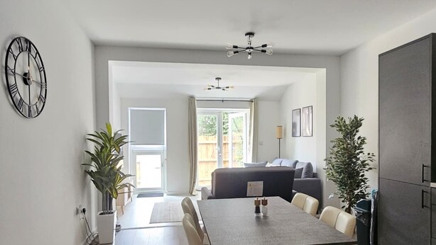 A modern kitchen with a dining area, a clock, and a view to the outside. - Luxury Flat 10 Mins from Station + Bike ! (Cambridge)