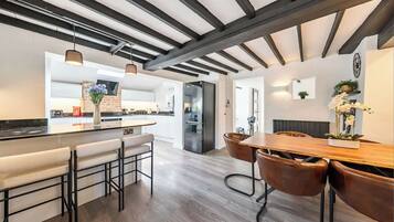 A modern kitchen with a bar area, wooden flooring, and pendant lighting.