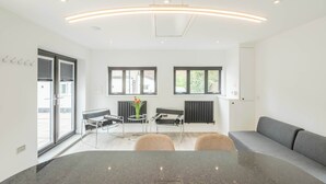 A modern interior with a dining area, seating, and a view through the windows. - Stargazing copper tub backing onto RSPB reserve (Cambridge)