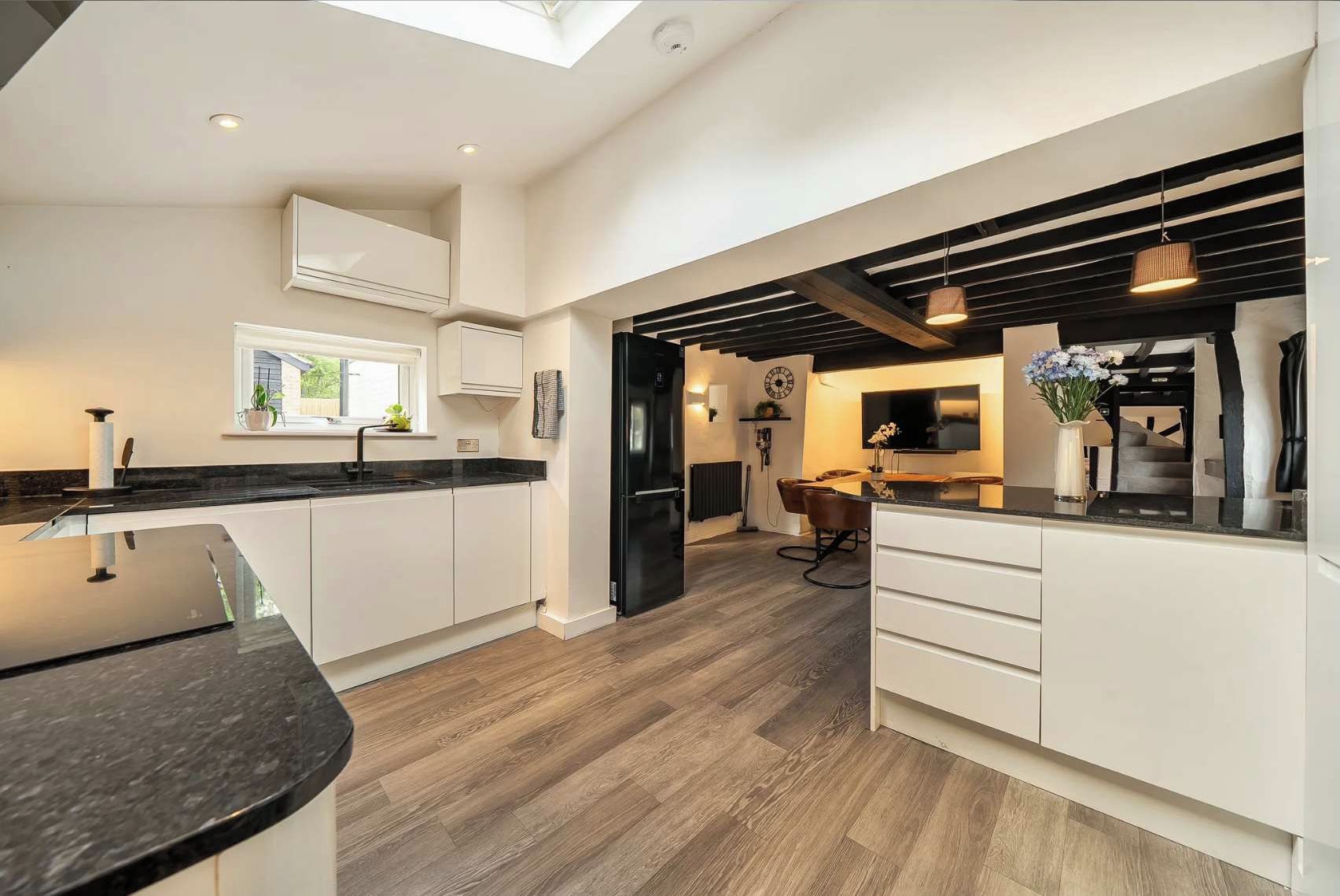 Open-plan Kitchen and Living Area: Spacious room combining cream cabinetry with black worktops, exposed timber beams, wa