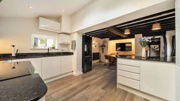 Open-plan Kitchen and Living Area: Spacious room combining cream cabinetry with black worktops, exposed timber beams, wa