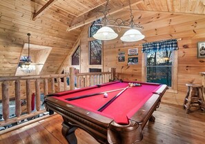 Ein Holzinterieur mit Billardtisch, Holzbalkendecke und einem Fenster mit Blick.