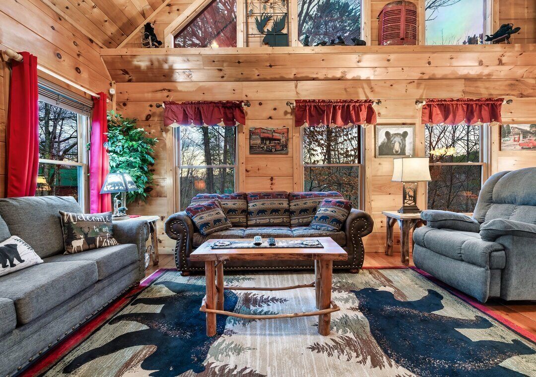 Een gezellig chaletinterieur met houten plafond, een bank, een stoel en een bijzettafeltje.