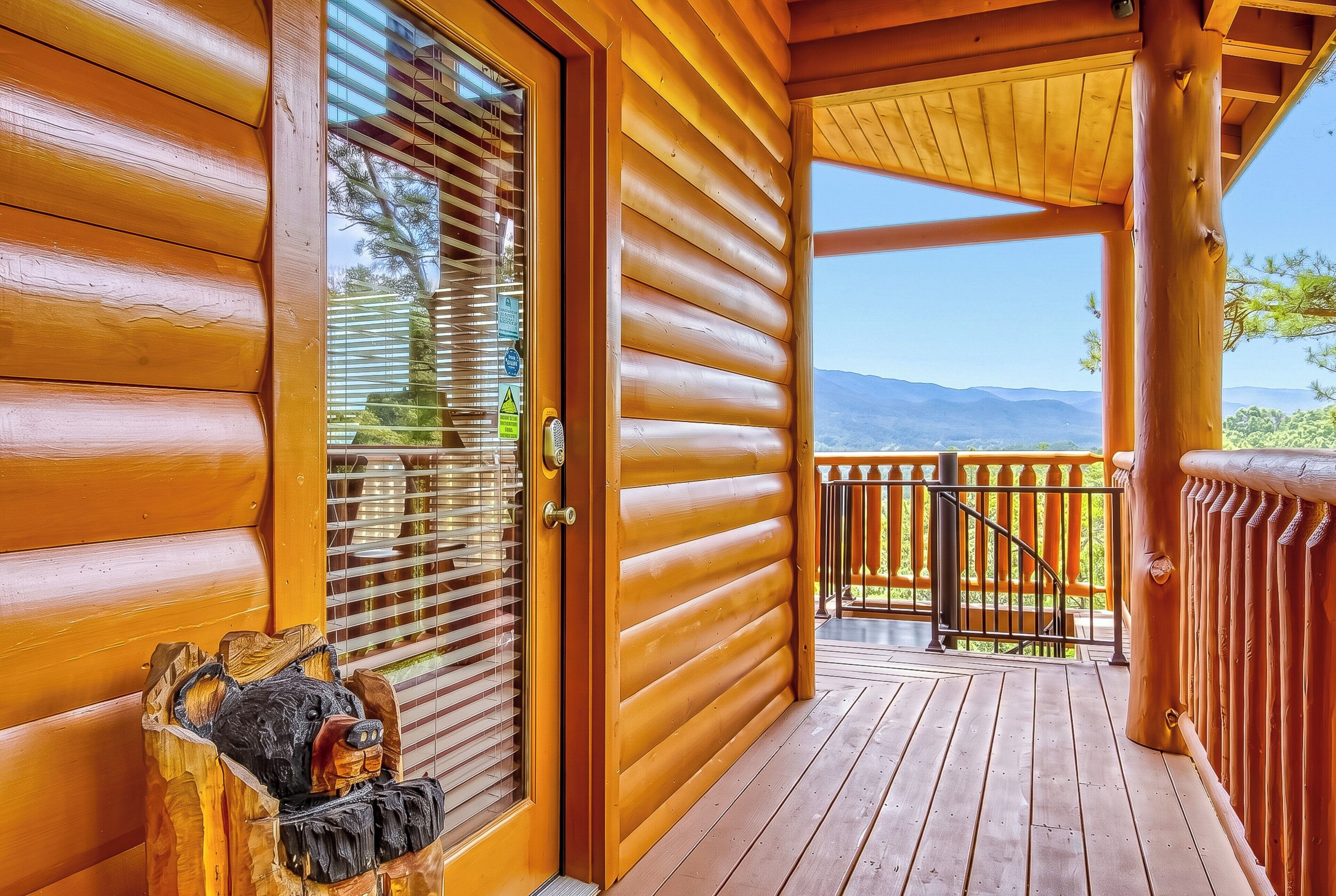A wooden cabin with a porch, a door with a window, and a view of mountains.
